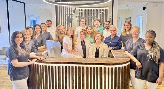 Das Team der Zahnarztpraxis Zahnärzte für Erftstadt steht gemeinsam an der Rezeption. Moderne Praxis mit freundlichem Personal.